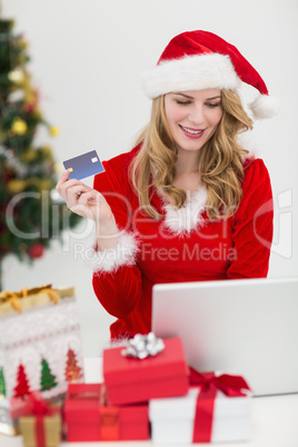 Festive blonde shopping online with laptop