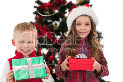 Festive little siblings smiling at camera holding gifts