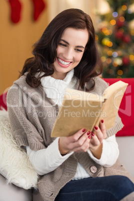 Smiling brunette reading on the couch at christmas