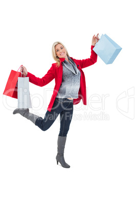 Happy blonde in winter clothes holding shopping bags