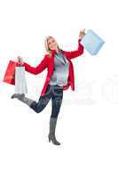 Happy blonde in winter clothes holding shopping bags