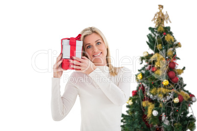 Festive blonde holding gift by the tree