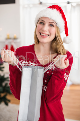 Festive blonde opening gift bag while looking at the camera