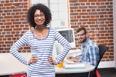Smiling businesswoman with hands on hips in office