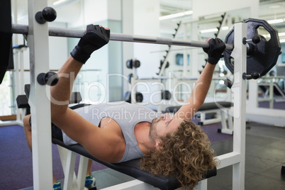 Young muscular man lifting barbell in gym