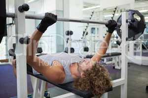 Young muscular man lifting barbell in gym