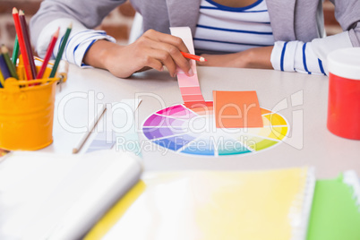 Mid section of designer with color samples at desk