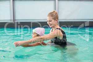 Cute little girl learning to swim with coach