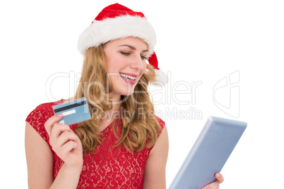 Festive blonde woman using her credit card and tablet pc