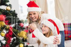 Festive mother and daughter decorating christmas tree