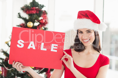 Festive brunette holding sale sign