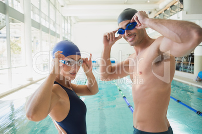 Fit couple swimmers by pool at leisure center