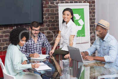 Team in meeting with recycling symbol on whiteboard
