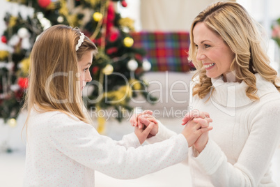 Festive mother and daughter beside christmas tree