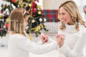 Festive mother and daughter beside christmas tree