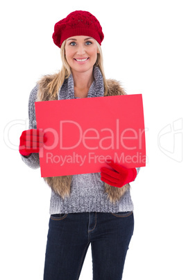 Blonde in winter clothes holding red sign