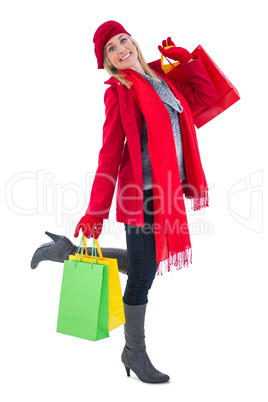 Happy blonde in winter clothes holding shopping bags