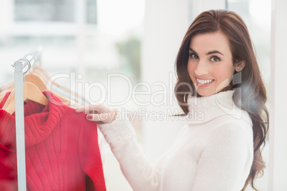 Smiling brunette looking at clothes on rail