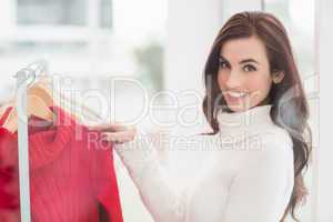 Smiling brunette looking at clothes on rail