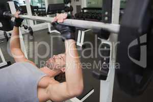 Young muscular man lifting barbell in gym