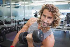 Young man exercising with dumbbell in gym