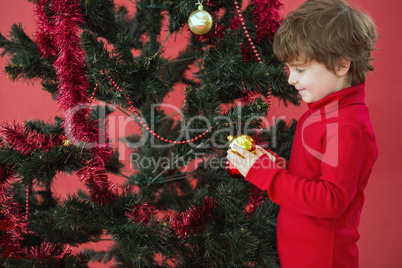 Festive little boy hanging a bauble