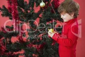 Festive little boy hanging a bauble