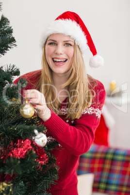 Smiling woman hanging christmas decorations on tree