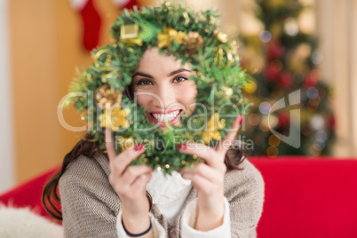 Brunette on the couch showing wreath at christmas
