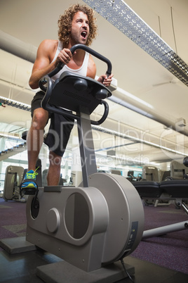 Determined man working out on exercise bike at gym