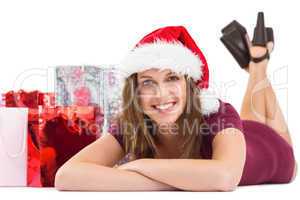 Festive brunette smiling at camera with gift bags behind her