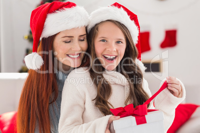 Festive mother and daughter on the couch with gift