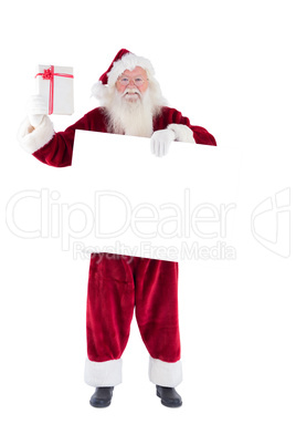 Santa shows a present while holding sign