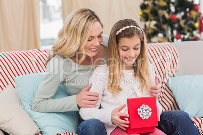 Daughter opening christmas gift with mother