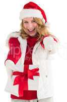 Festive blonde holding christmas gift and pointing her finger