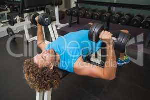 Young man exercising with dumbbells in gym