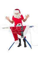 Surprised santa claus ironing his jacket