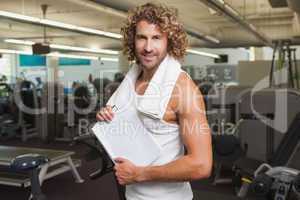 Smiling handsome trainer with clipboard in gym