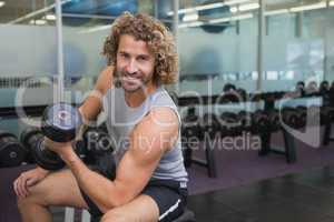 Young man exercising with dumbbell in gym