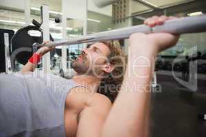 Young muscular man lifting barbell in gym