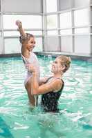 Cute little girl learning to swim with coach