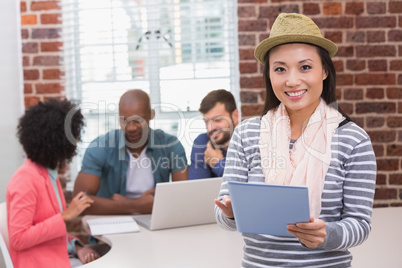 Woman using digital tablet with colleagues behind in office