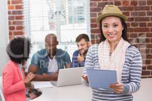 Woman using digital tablet with colleagues behind in office