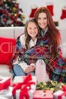 Festive mother and daughter wrapped in blanket