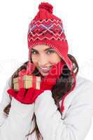 Surprised brunette in winter clothes holding gift