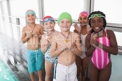 Cute little kids standing poolside with medals