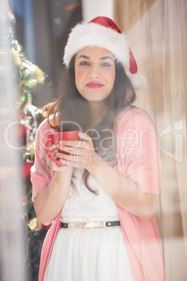 Brunette in santa hat holding mug