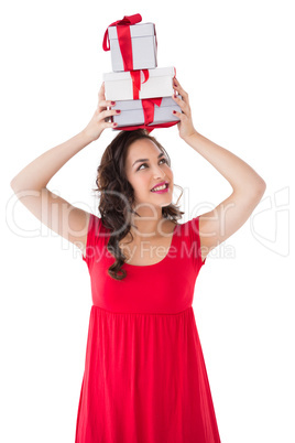 Happy brunette in red dress holding many gifts