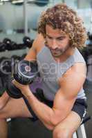 Young man exercising with dumbbell in gym