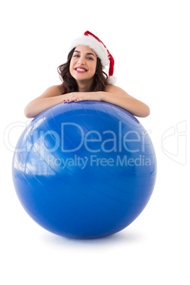 Festive fit brunette leaning on exercise ball